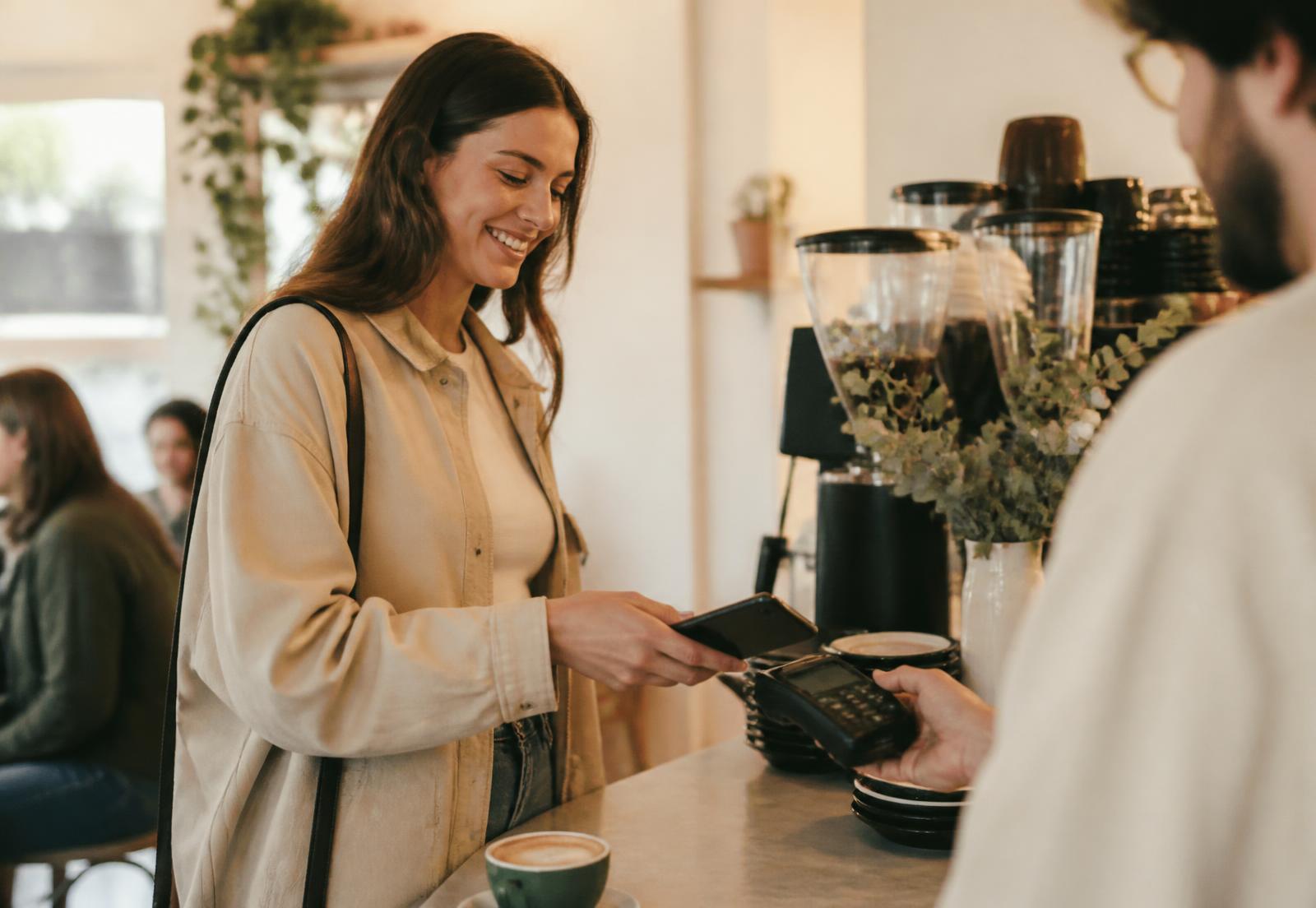 Customer paying with a phone at a coffee shop counter